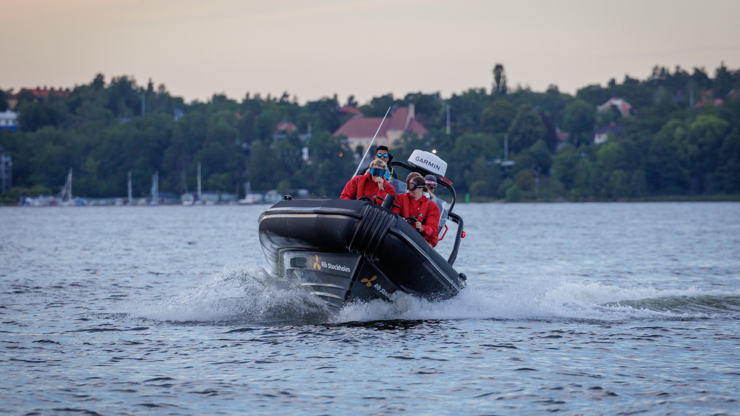 A rescue boat with three people in life jackets speeding on a lake.
