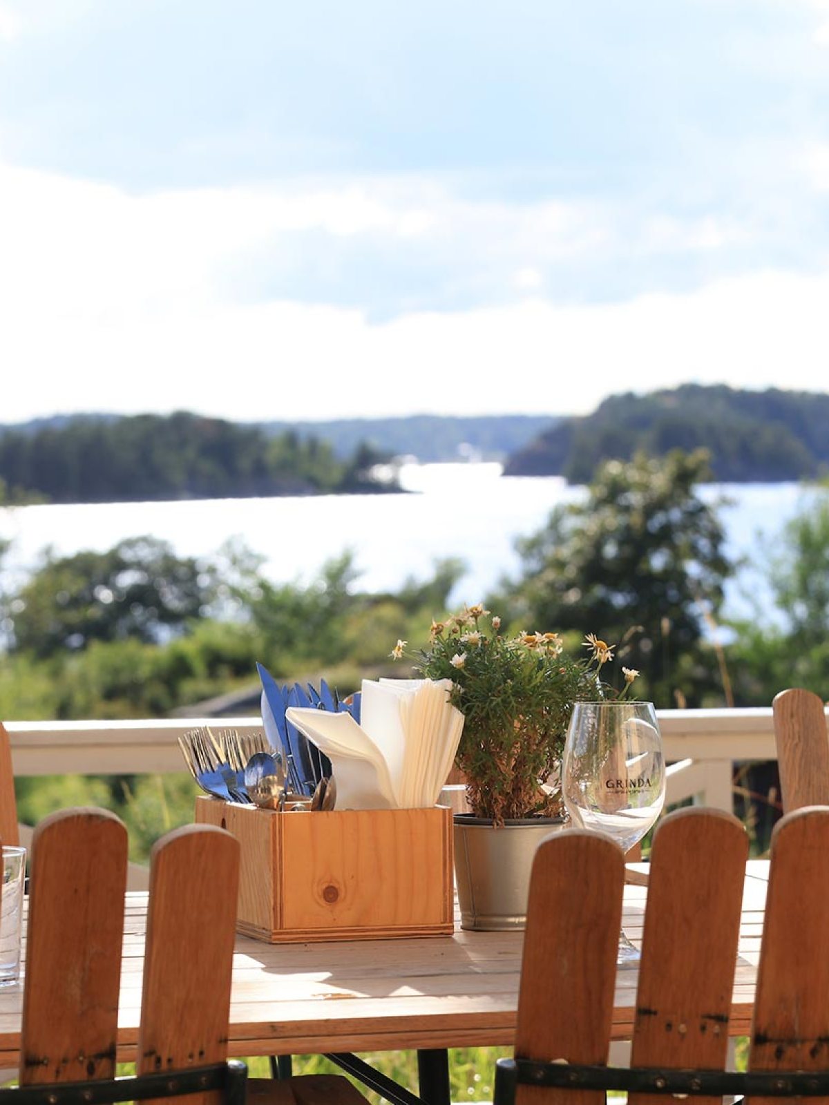 Outdoor dining table with chairs overlooking a scenic lake and islands.