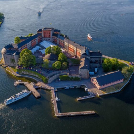 Aerial view of a fortress on an island surrounded by water with several boats nearby.